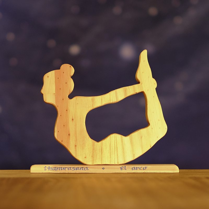 Postura de yoga el arco en madera, sobre base con nombre en sánscrito y castellano.