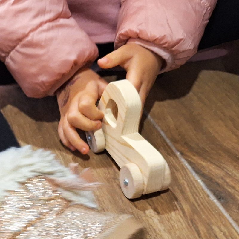 Coche de madera tipo camioneta, con niña de 4 años