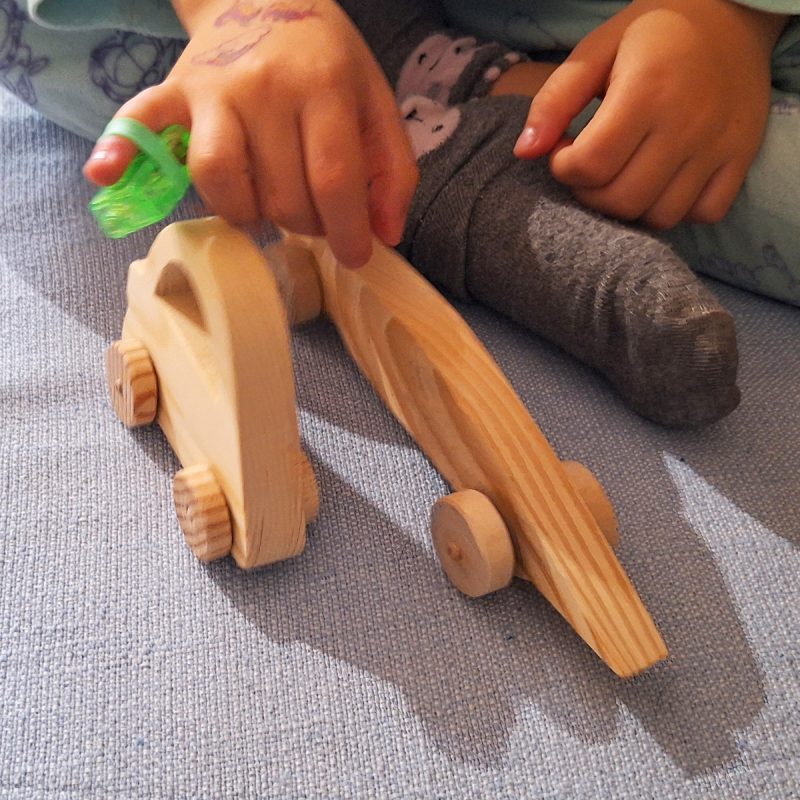 Coche de madera, bólido de carreras, con niña