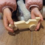 Coche de carreras de madera- en manos de una niña de 4 años